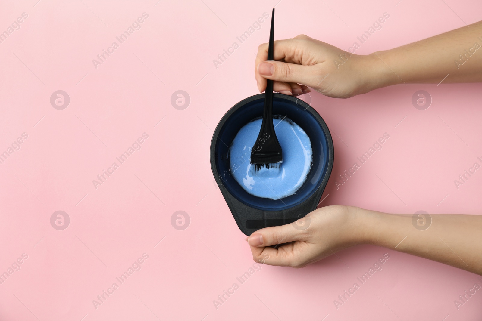 Photo of Woman preparing dye for hair coloring on pink background, top view. Space for text