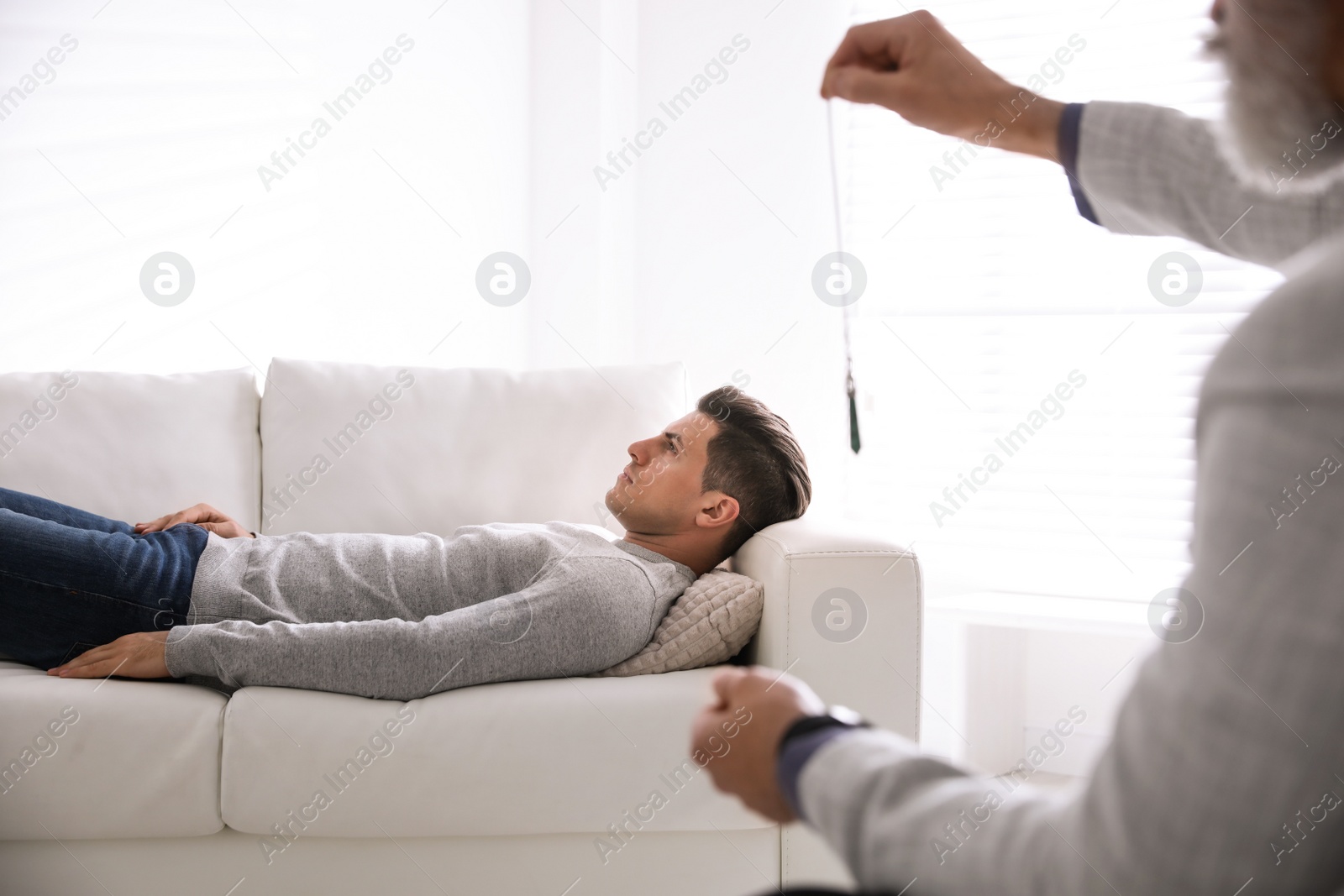 Photo of Psychotherapist using pendulum during hypnotherapy   session in office