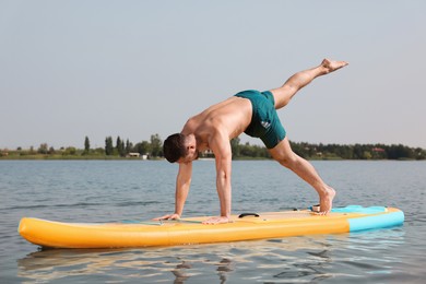 Man practicing yoga on SUP board on river