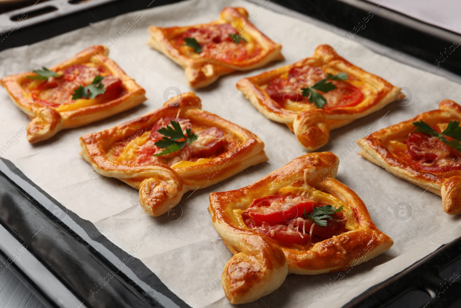 Photo of Fresh delicious puff pastry with tasty filling on baking sheet, closeup