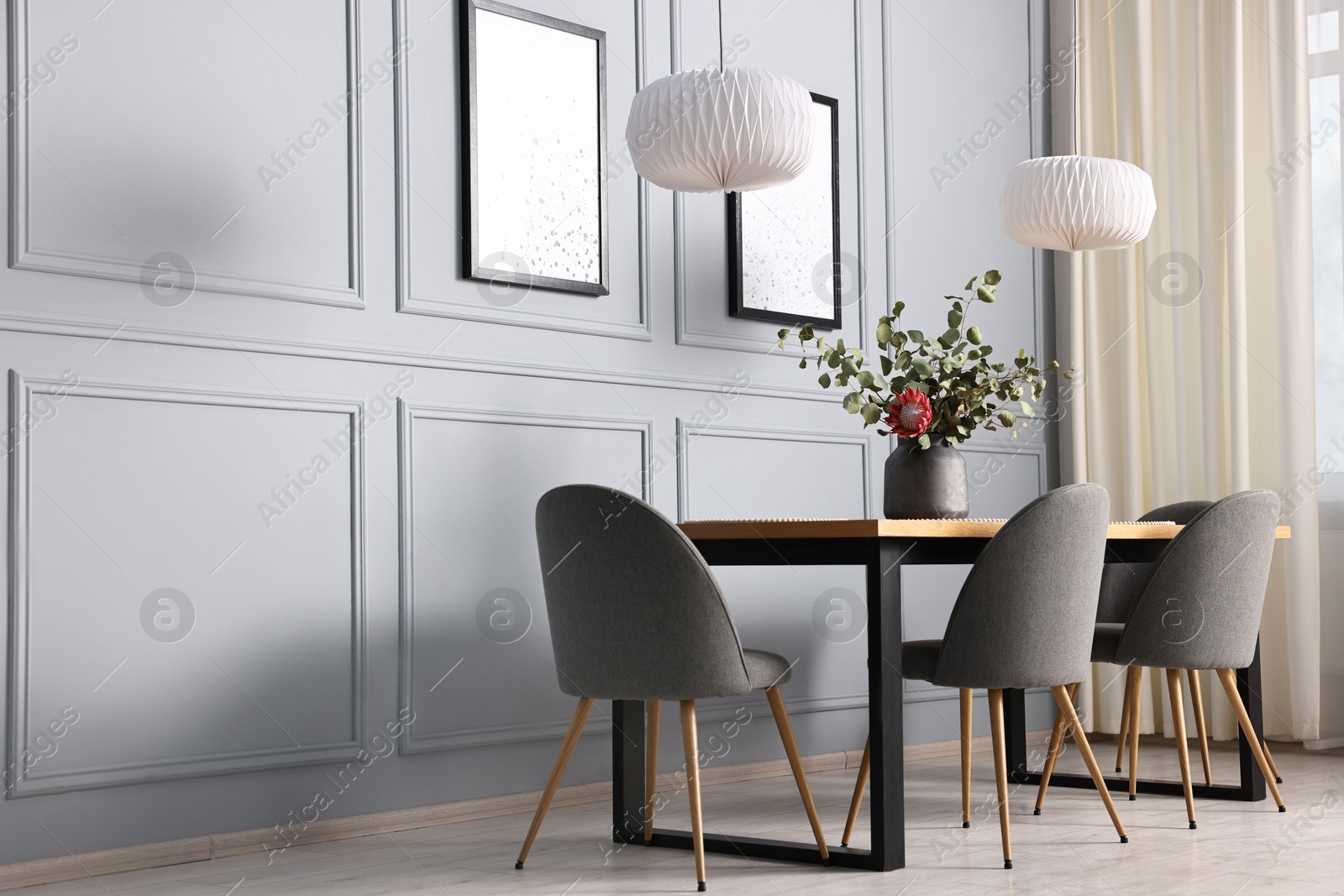 Photo of Soft chairs, table and vase with plants in stylish dining room