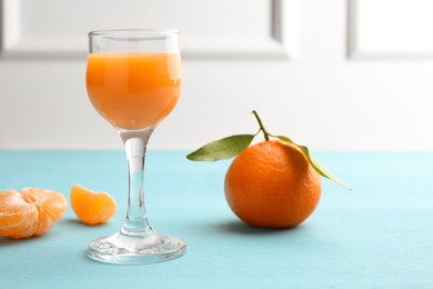 Delicious tangerine liqueur and fresh fruits on light blue wooden table