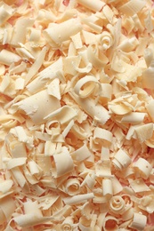 Pile of white chocolate curls as background, top view