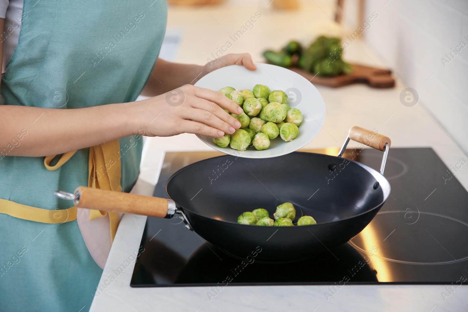 Photo of Young woman cooking on stove in kitchen, closeup