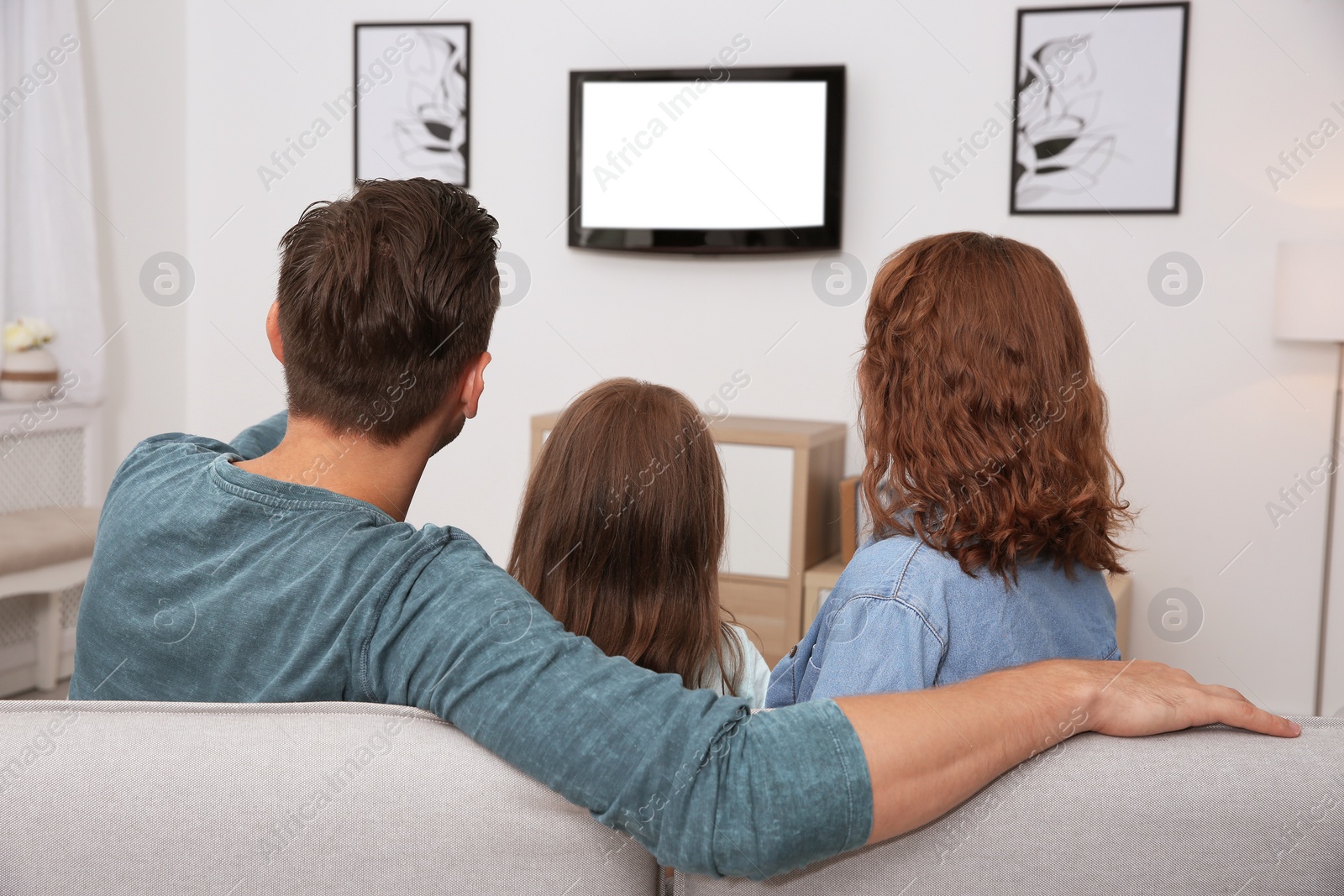 Photo of Family watching TV in room at home