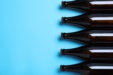 Bottles of beer on light blue background, flat lay. Space for text