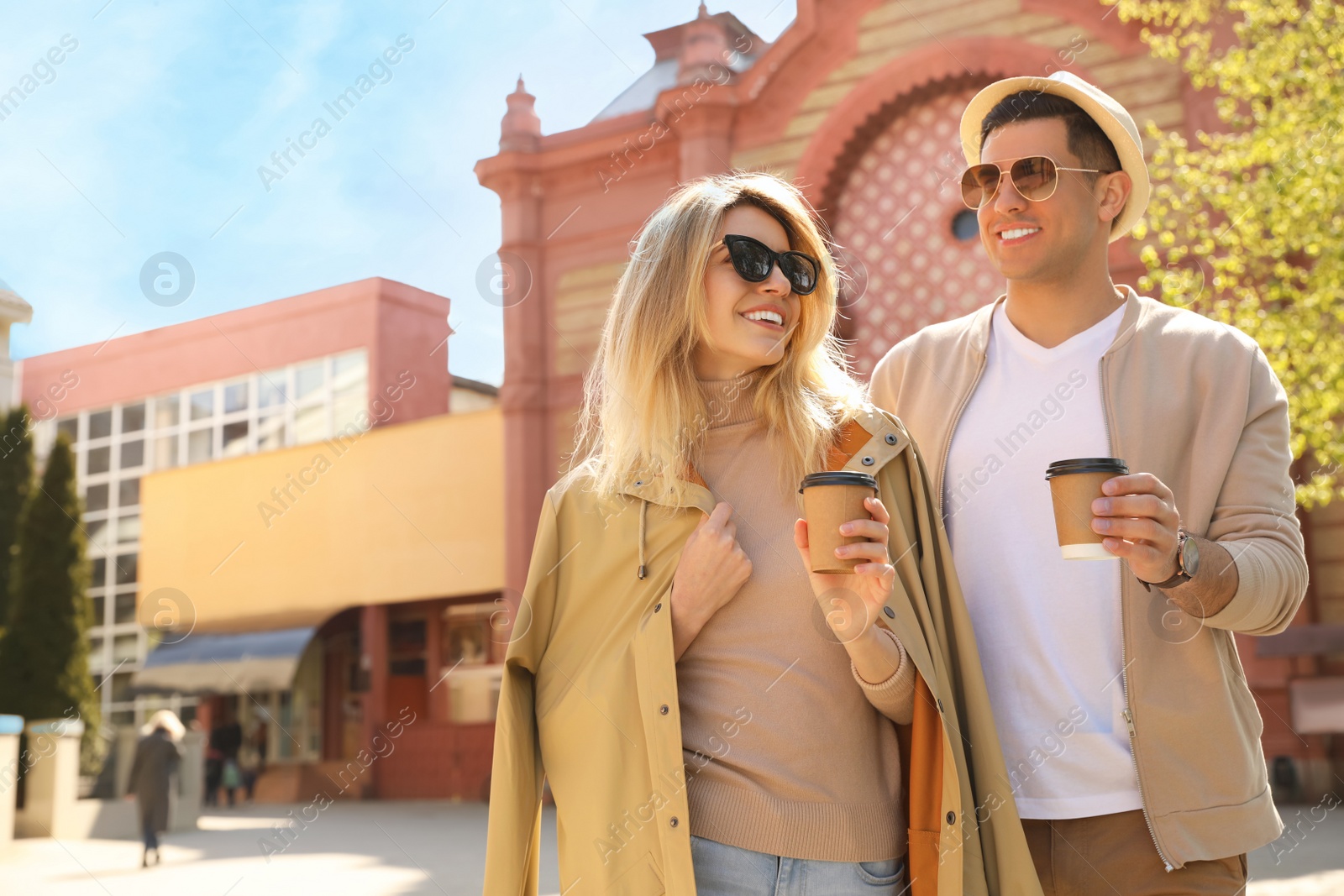 Photo of Happy couple with coffee on city street in morning