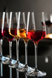 Row of glasses with different wines on bar counter against blurred background