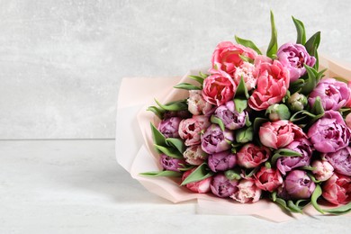 Photo of Bouquet of beautiful tulips on white table, closeup. Space for text