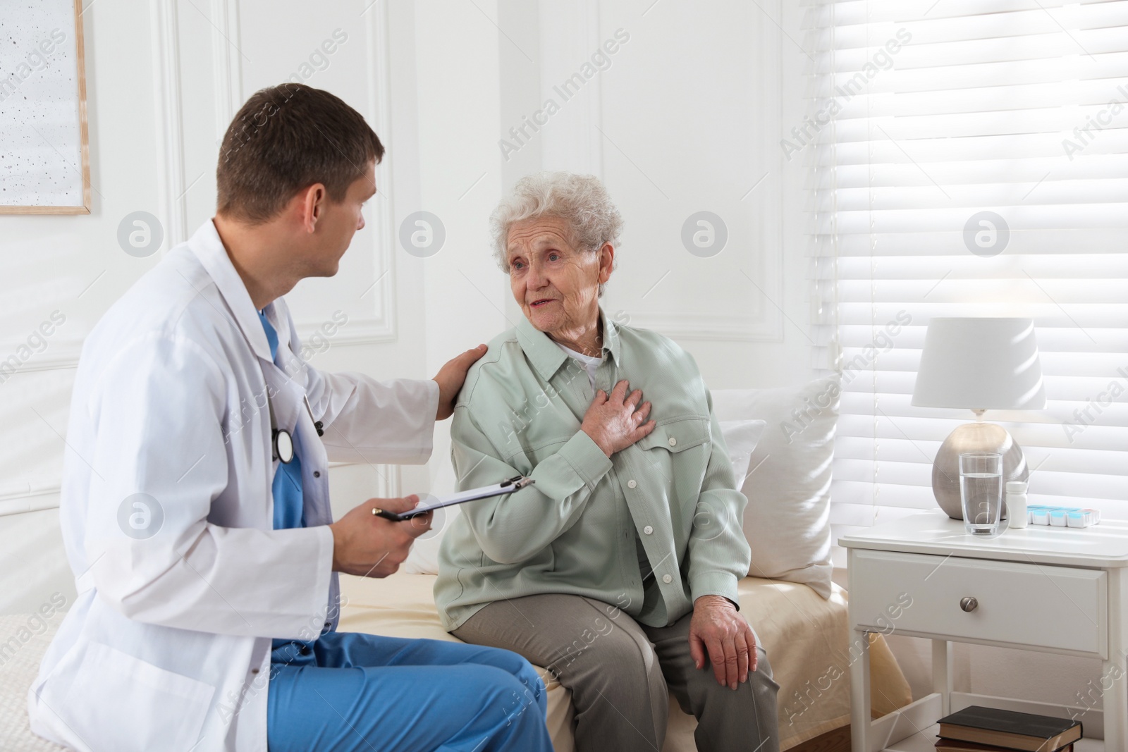 Photo of Caregiver examining senior woman in room. Home health care service