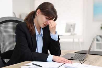 Overwhelmed woman suffering at table in office