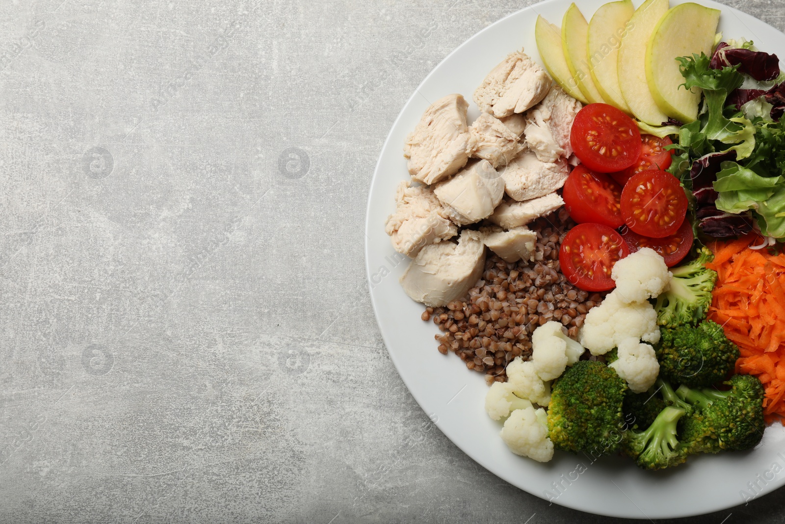 Photo of Balanced diet and healthy foods. Plate with different delicious products on grey table, top view. Space for text