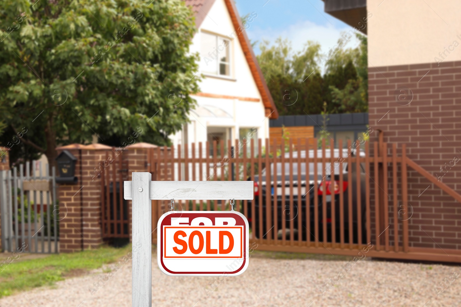 Image of Red sale sign with Sold sticker near house