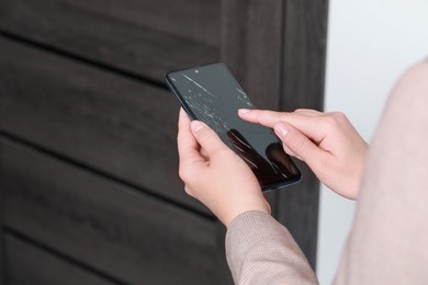 Photo of Woman holding damaged smartphone near door, closeup. Device repairing