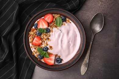 Photo of Bowl with yogurt, berries and granola on brown table, flat lay
