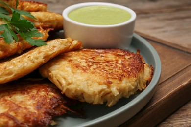 Tasty parsnip cutlets with sauce on wooden table, closeup