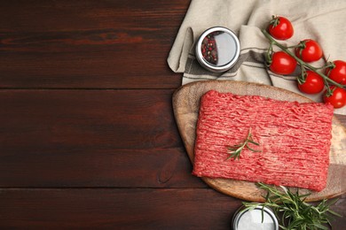 Photo of Raw fresh minced meat, tomatoes and other ingredients on wooden table, flat lay. Space for text