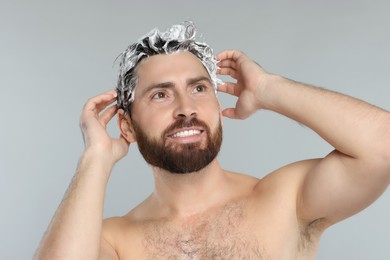 Happy man washing his hair with shampoo on grey background