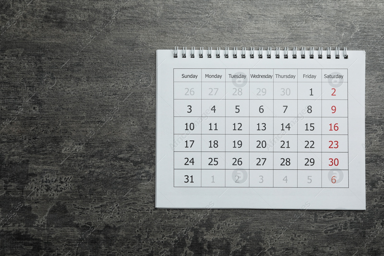 Photo of Paper calendar on grey stone background, top view. Space for text