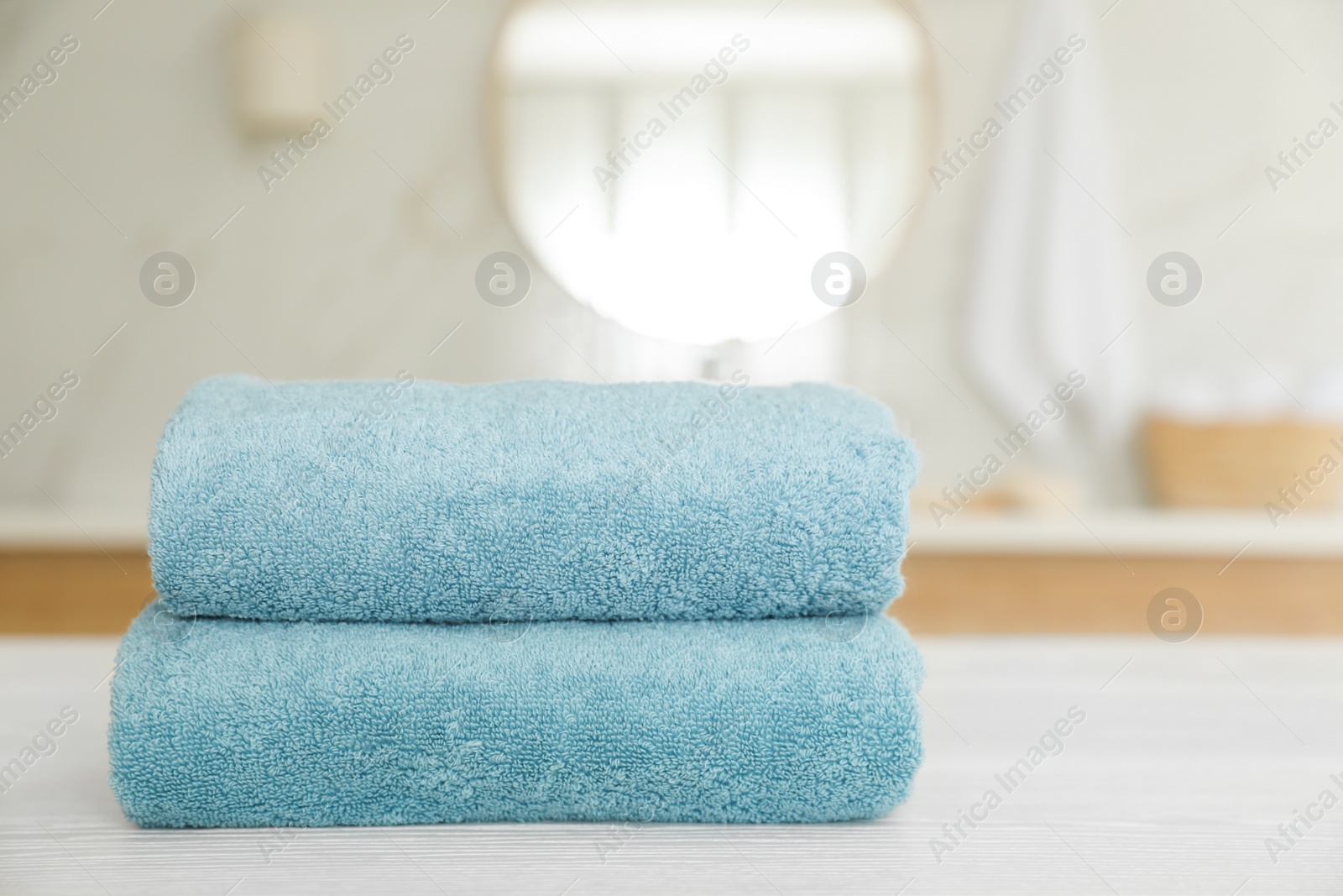 Photo of Stack of clean towels on white wooden table in bathroom