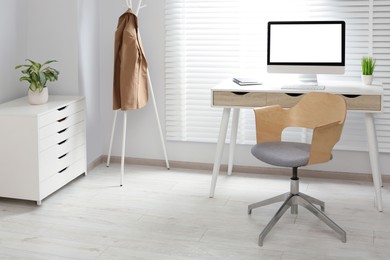 Stylish office interior with comfortable chair, desk and computer