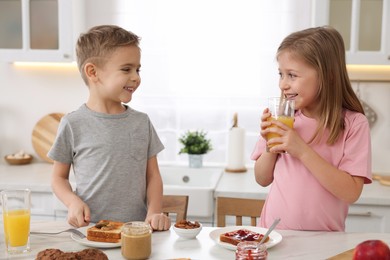 Little children having breakfast at table in kitchen