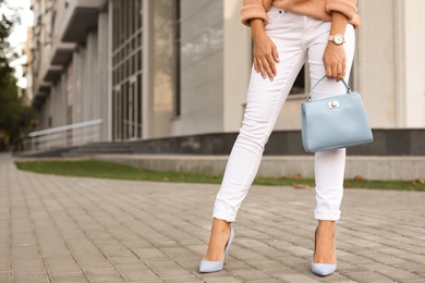 Photo of Young woman with stylish light blue bag on city street, closeup