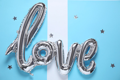 Foil balloon in shape of word LOVE on color background, top view