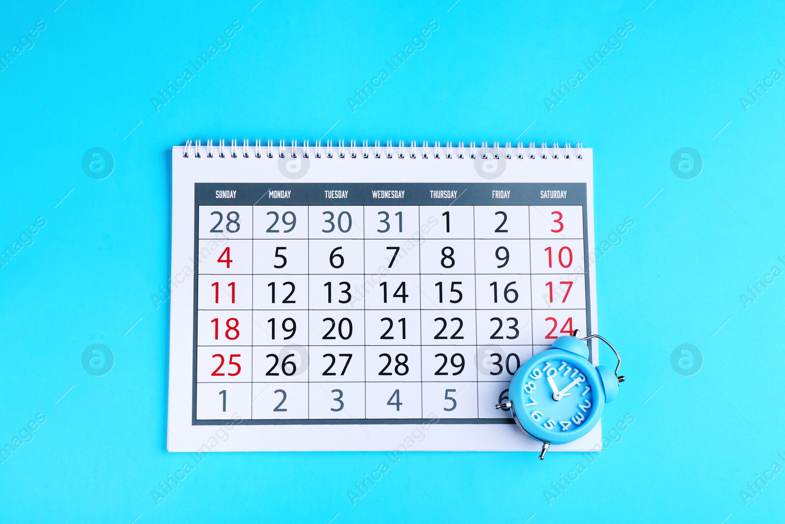 Photo of Calendar and alarm clock on light blue background, flat lay