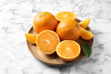 Photo of Plate with ripe oranges on marble background