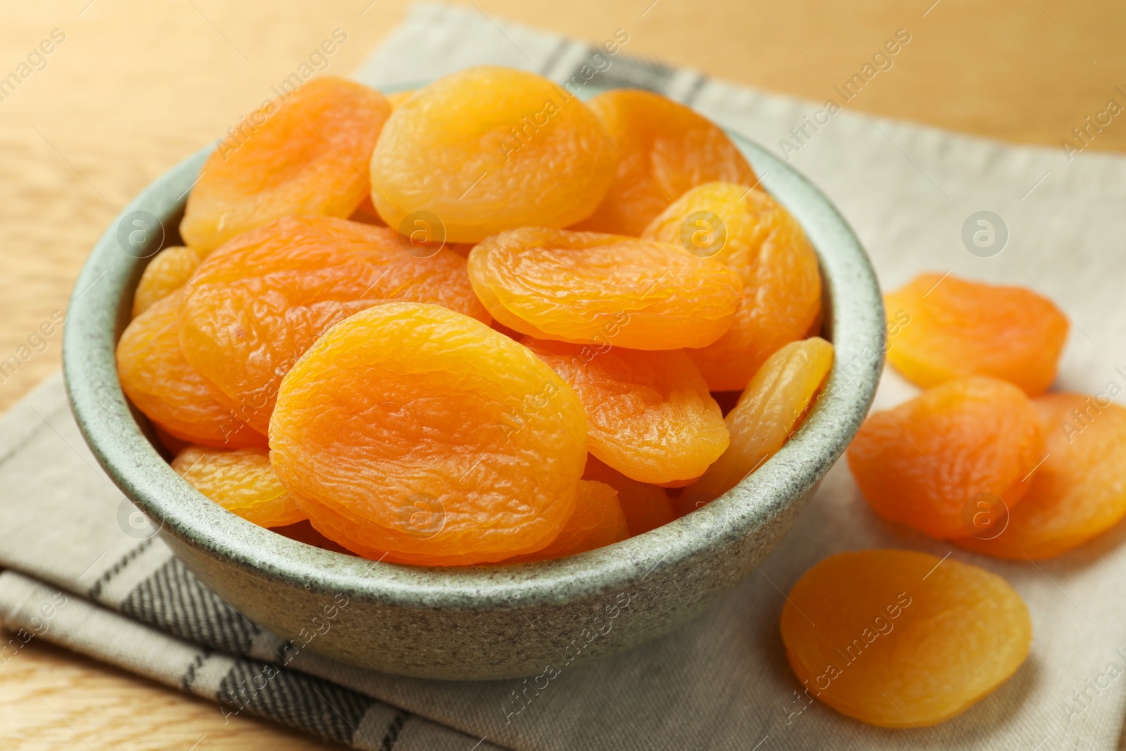 Photo of Bowl of tasty apricots on wooden table, closeup. Dried fruits