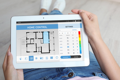 Woman using energy efficiency home control system on tablet, closeup