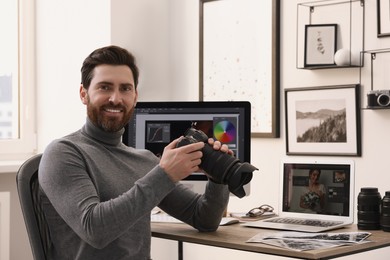 Photo of Professional photographer with digital camera at table in office