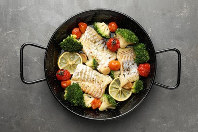 Photo of Tasty cod cooked with vegetables in frying pan on grey table, top view