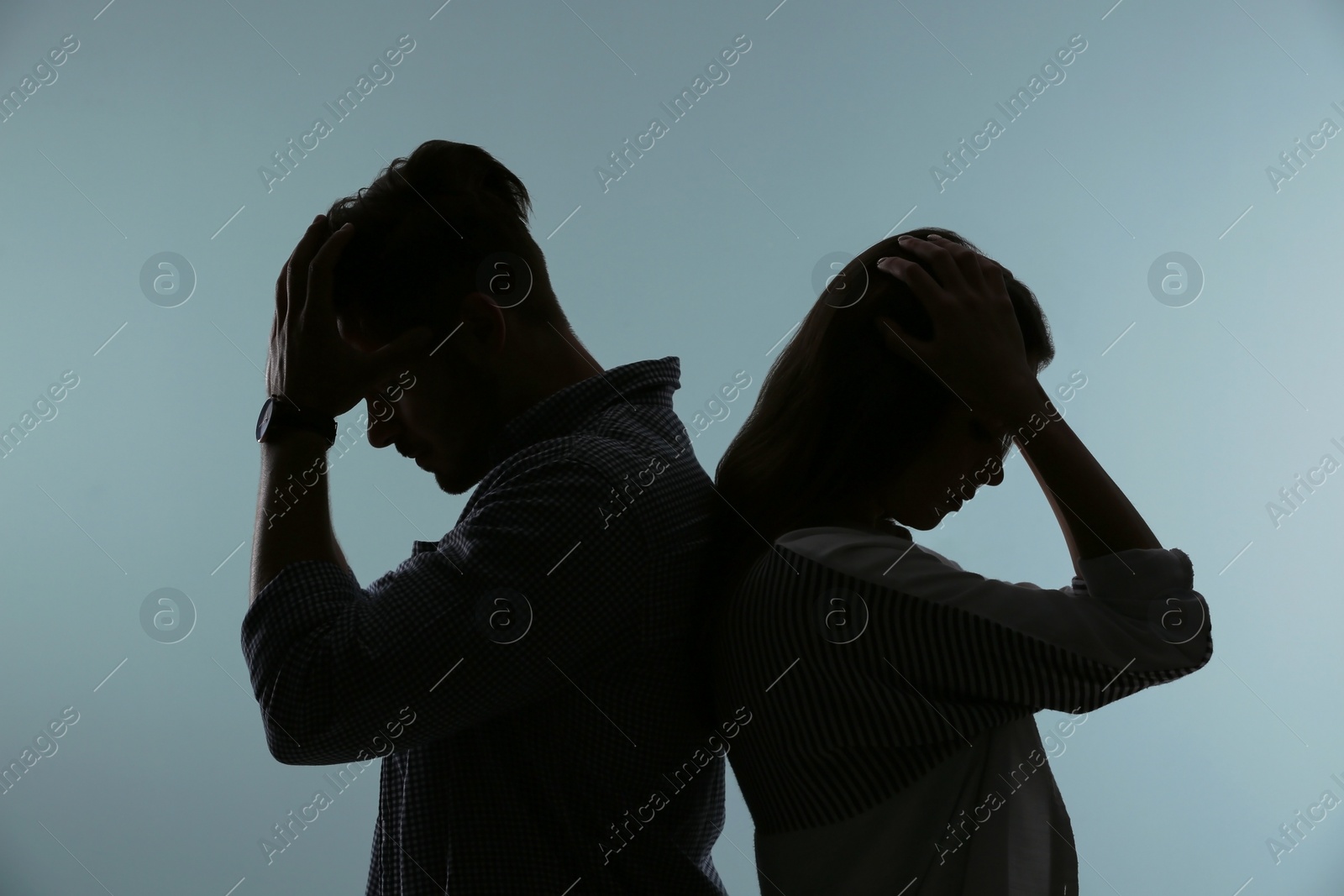 Photo of Silhouette of upset couple on color background. Relationship problems