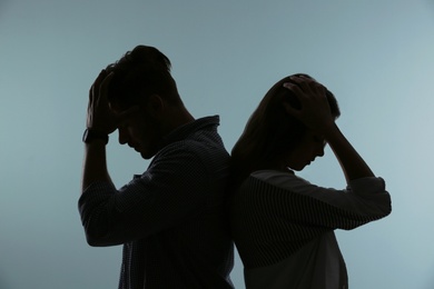 Silhouette of upset couple on color background. Relationship problems