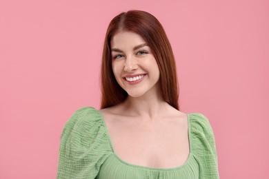 Portrait of smiling woman with freckles on pink background
