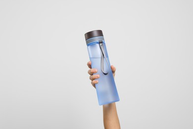 Photo of Woman holding bottle of water on light grey background, closeup