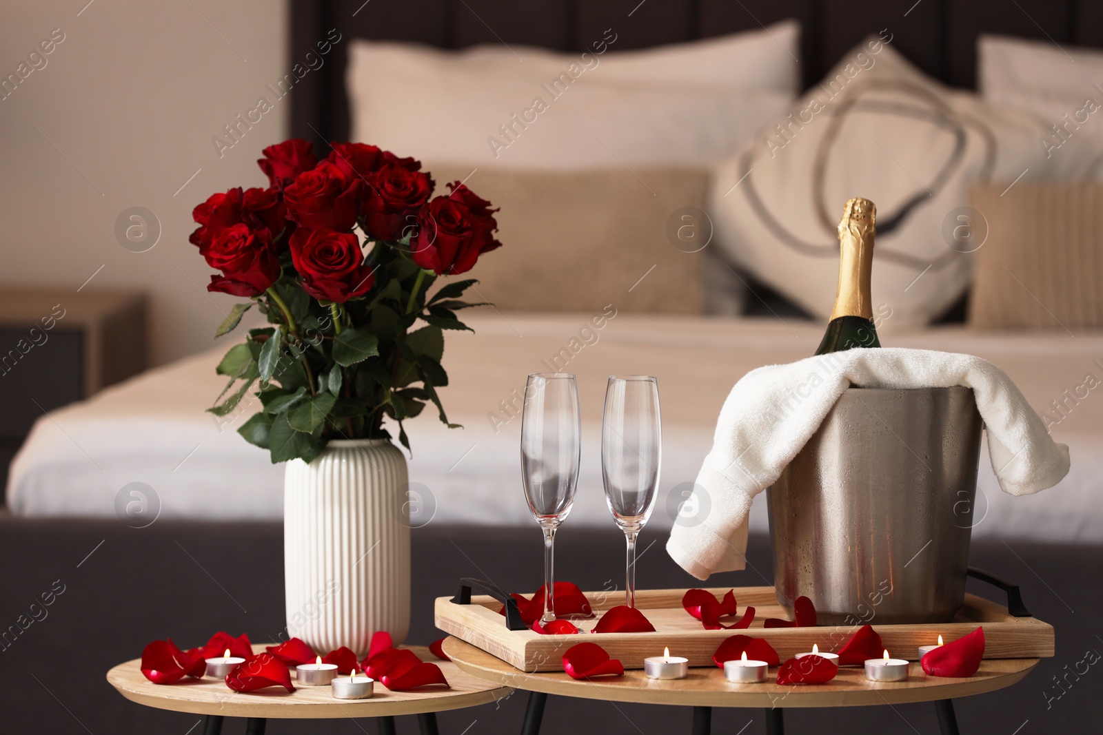 Photo of Honeymoon. Sparkling wine, glasses and bouquet of roses on wooden table in room