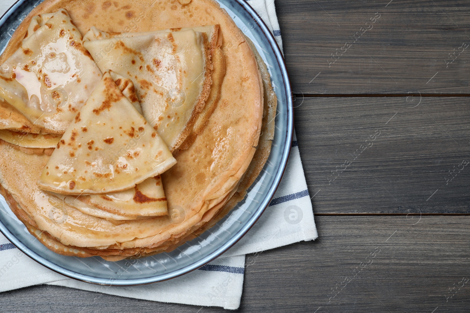 Photo of Delicious crepes on wooden table, top view. Space for text