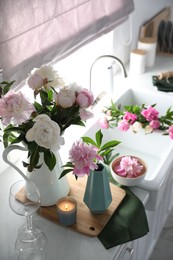 Beautiful peonies in vases on kitchen counter