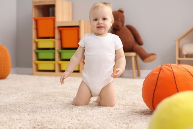 Photo of Children toys. Cute little boy and soft toy ball on rug at home