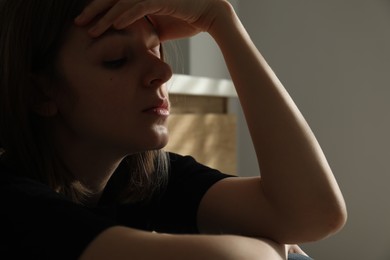 Sad young woman on blurred background, closeup