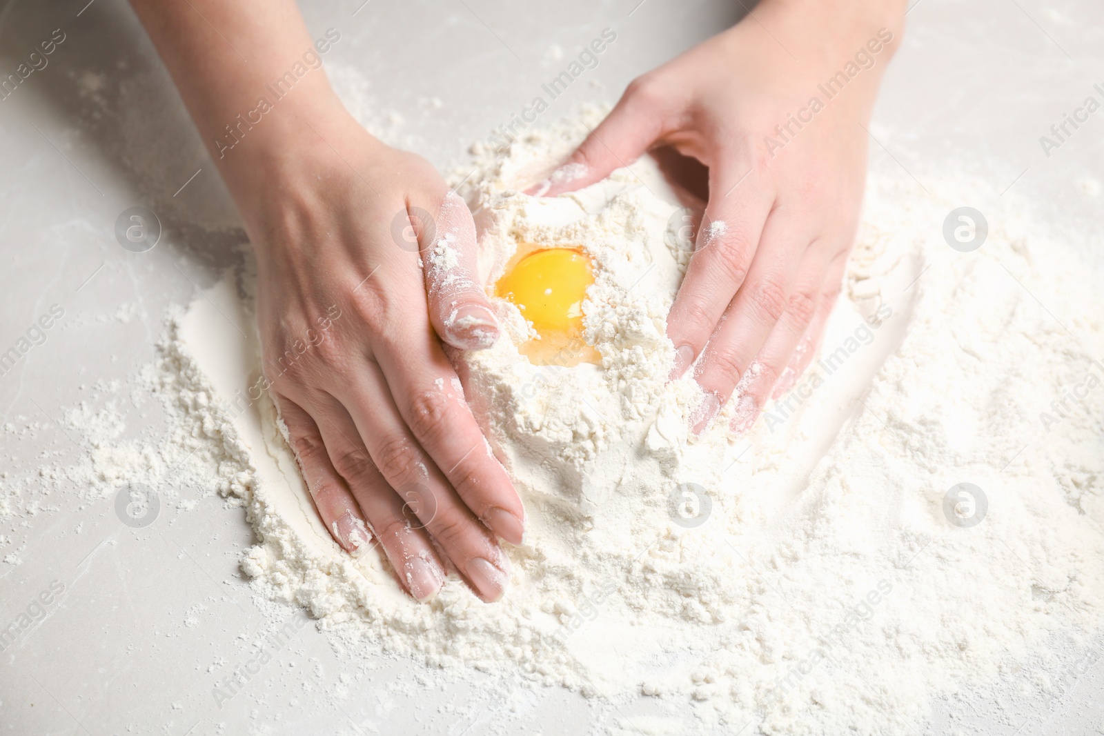 Photo of Woman mixing flour and egg on table