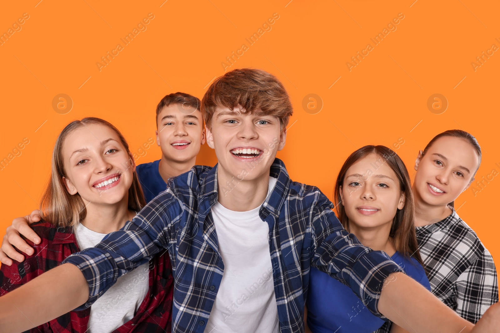 Photo of Group of happy teenagers taking selfie on orange background