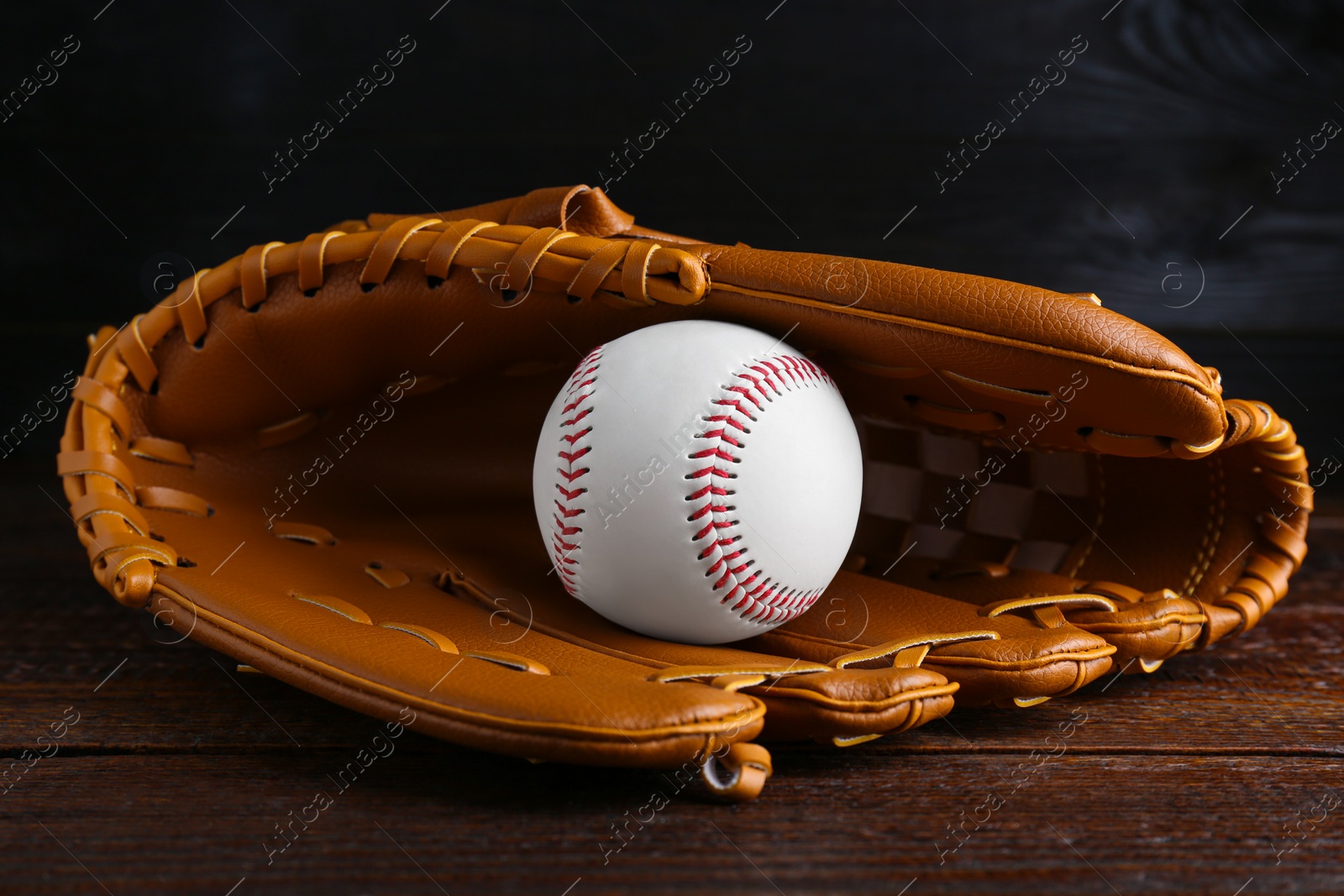 Photo of Leather baseball glove with ball on wooden table