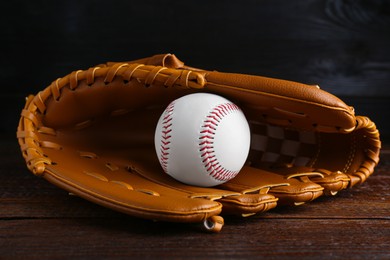 Photo of Leather baseball glove with ball on wooden table