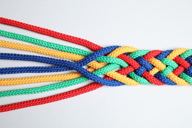 Photo of Braided colorful ropes isolated on white, top view. Unity concept