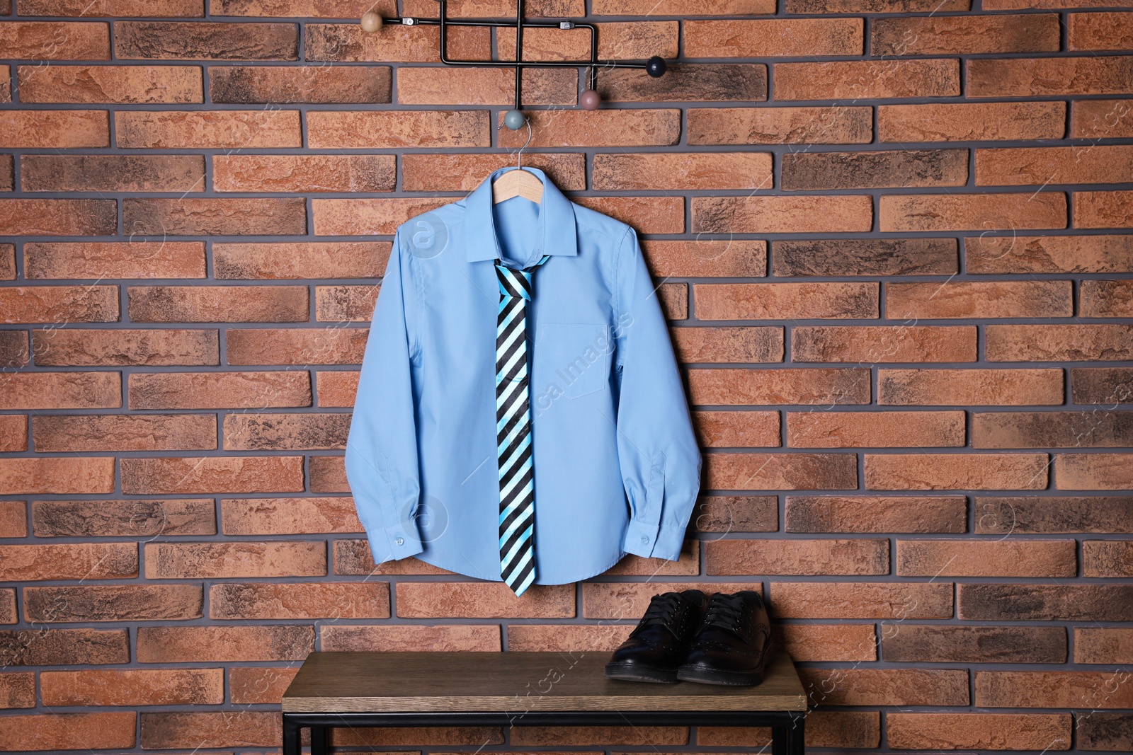 Photo of Shirt with tie hanging on brick wall. School uniform