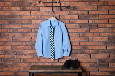 Photo of Shirt with tie hanging on brick wall. School uniform